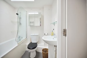 A bathroom with a glass-enclosed shower, a toilet, a sink, and a mirror. - Light by Regent's Canal (London)