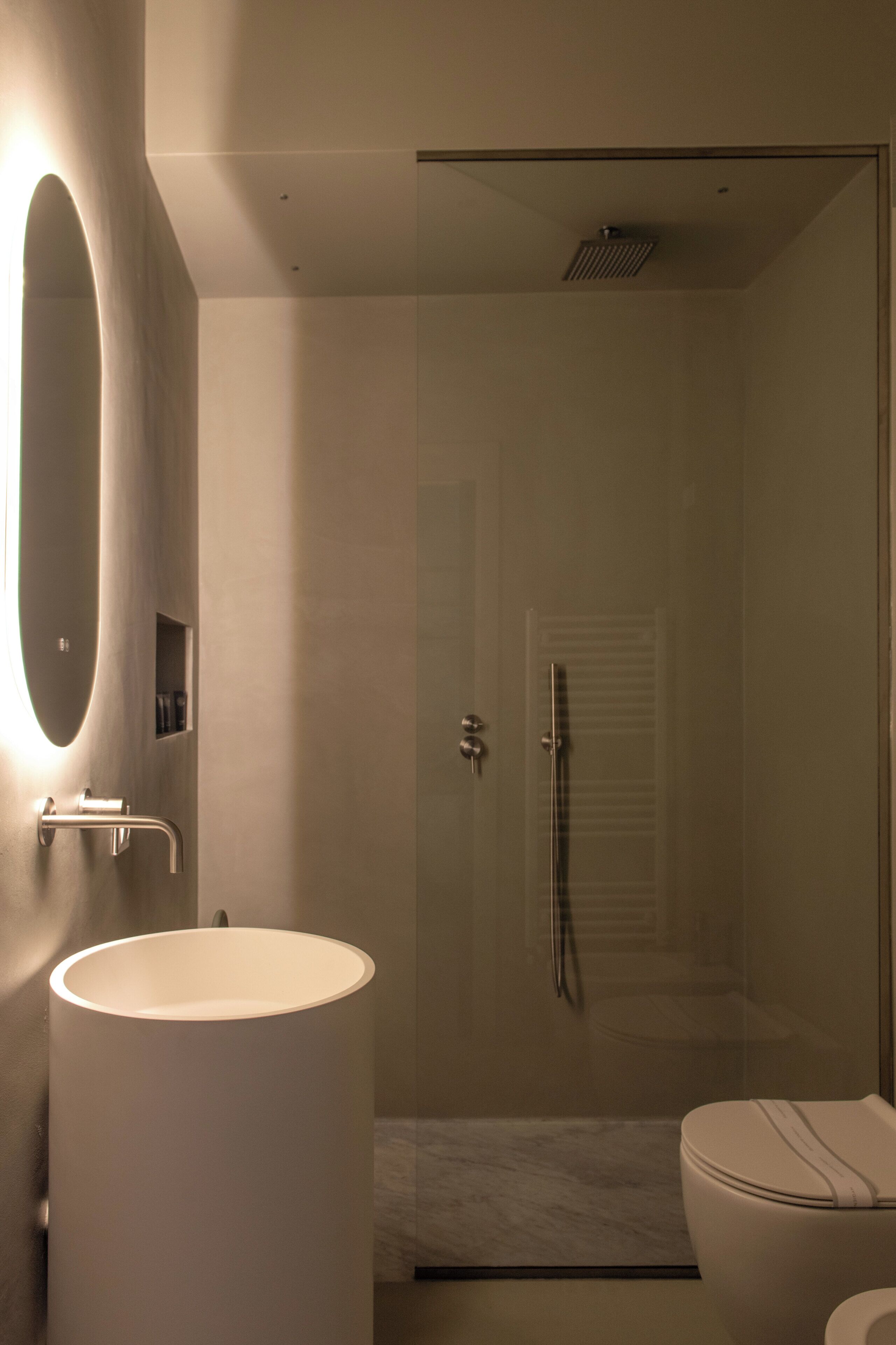 Un baño moderno con un lavabo ovalado grande, cabina de ducha con mampara de cristal y un inodoro.