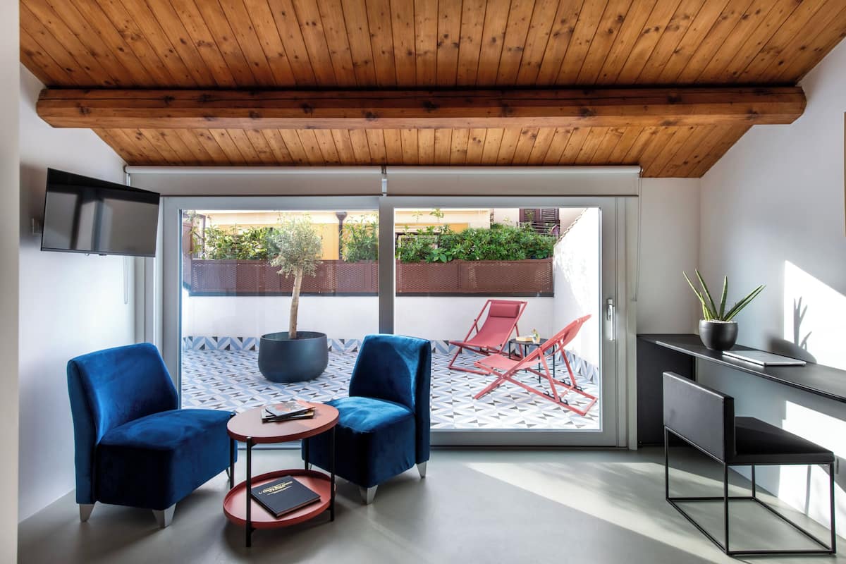 Una habitación moderna con techo de madera, televisor montado en la pared, sofá, mesita y escritorio con planta.