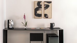 A modern office desk with a coffee machine, a vase with an orchid, and two abstract paintings. - Palazzo Achates (Palermo)