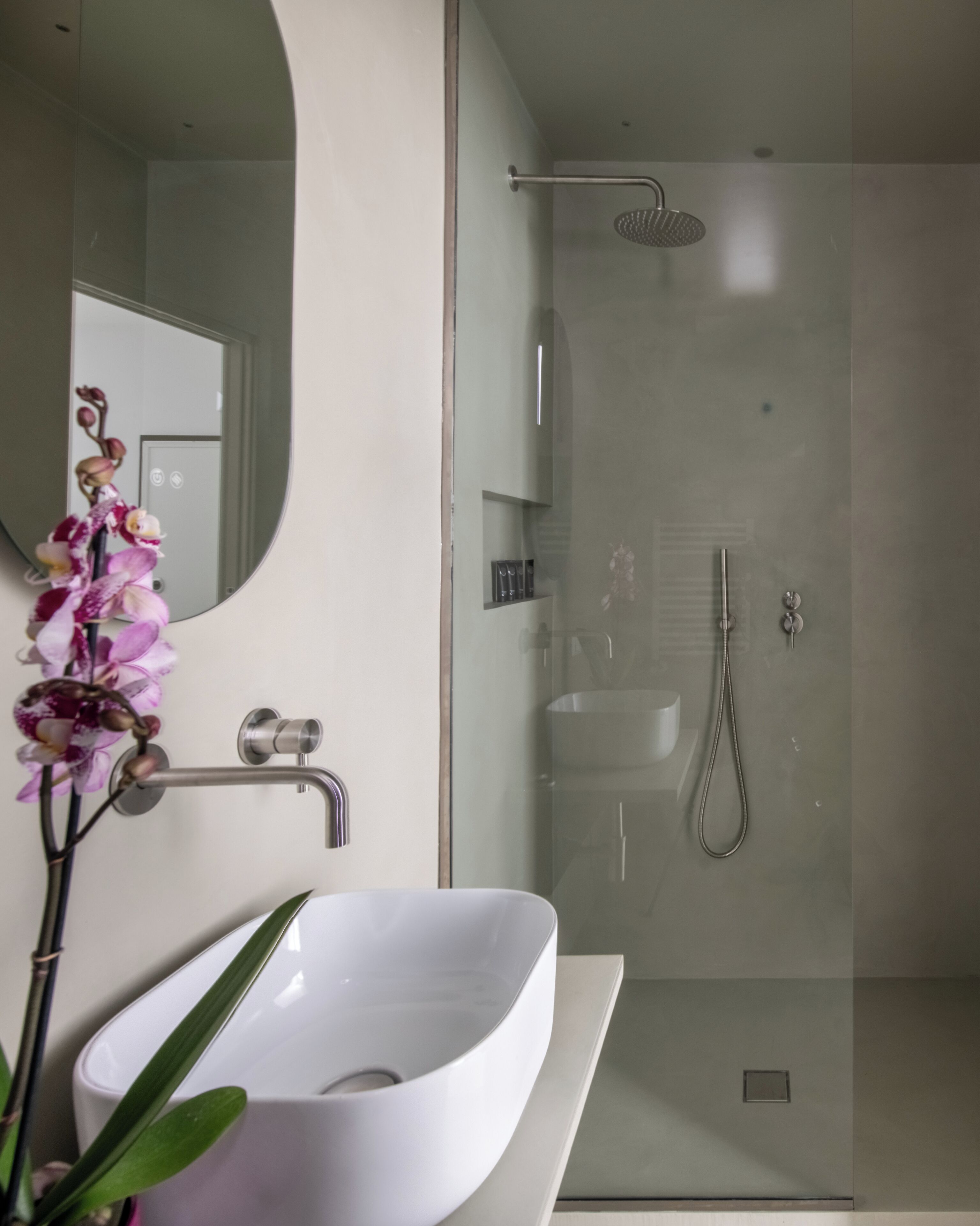 A modern bathroom with a white sink, a glass shower enclosure, and a mirror.
