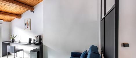 A modern living room with a sofa, a coffee table, a desk with a computer, and a large TV.