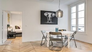 A modern dining area with a round table, chairs, a hanging light fixture, and a large window. - Bonne Nouvelle Beauty | 200m² of Parisian Elegance Near Opéra (Paris)