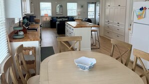 A spacious kitchen with white cabinetry, a dining area with a round table and chairs, and a living area with a sofa and a coffee table. - Fabulous 4-bedroom channel home with private dock in Cherry Grove Beach. (North Myrtle Beach)