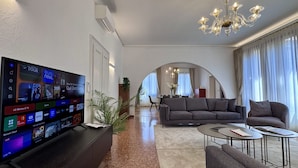 A modern living room with a flat-screen TV, a sofa, a coffee table, and a chandelier. - Angelo Prestige Canal View (Venice)
