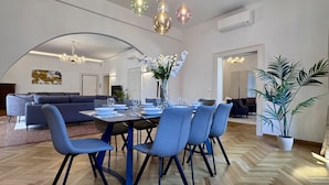 A modern dining area with a round table, blue chairs, and a vase of white flowers. - Angelo Prestige Canal View (Venice)