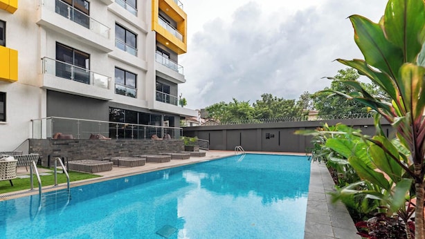 Une piscine avec des chaises longues et un bâtiment doté de balcons.