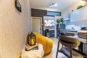 A modern kitchen with a dining area, a sofa, and a small table with a lantern. - Kilimani, Wilma Tower, Studio, Steam, Sauna, Pool &Gym (Nairobi)