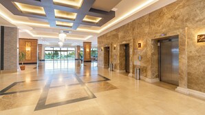 A spacious lobby with a modern design, featuring a marble floor, a large chandelier, and two elevators. - Casa Fora Beach Resort (Manavgat)