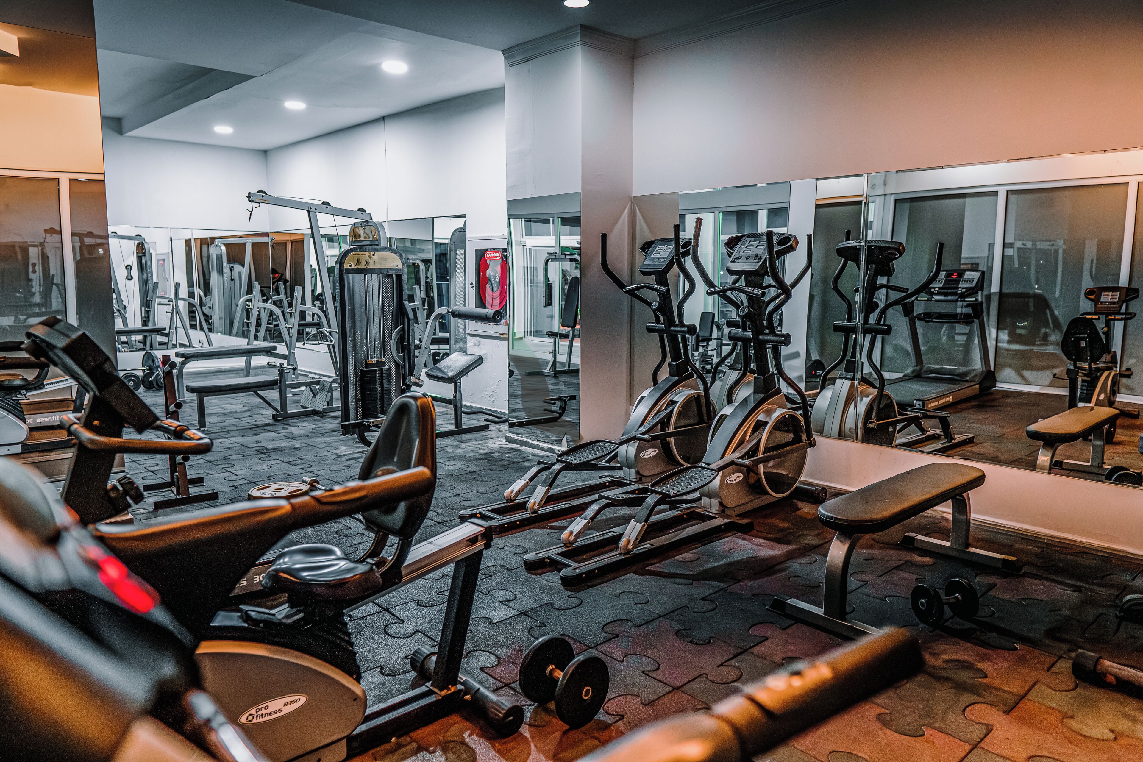 A gym with various exercise equipment, including treadmills, weight machines, and free weights.