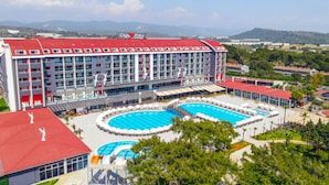 A hotel with multiple swimming pools, a red roof, and a view of the surrounding landscape. - Casa Fora Beach Resort (Manavgat)