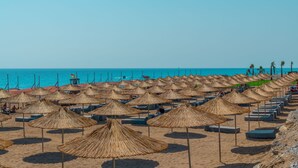 A beach with rows of thatched umbrellas and lounge chairs. - Casa Fora Beach Resort (Manavgat)