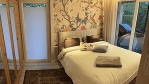 A bedroom with a large bed, a patterned rug, a window with a view, and a door leading outside. - Private vacation home with large terrace & garden - quiet location near Bodden/Baltic Sea (Saal)