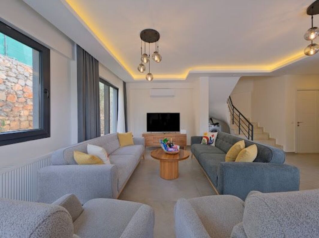 A modern living room with sofas, a TV, and a staircase.