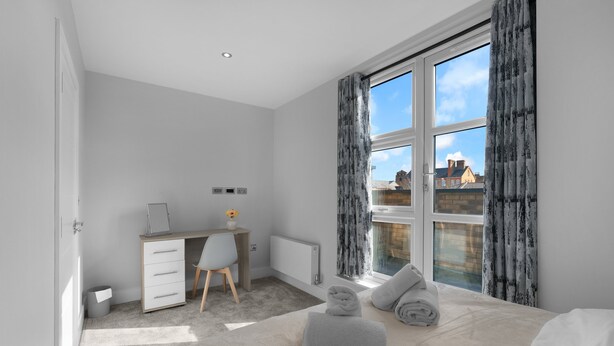 A bedroom with a bed, a desk, a chair, a radiator, and a window with curtains. - 4BDR 3BA Family Home Garden in Isleworth (Isleworth)