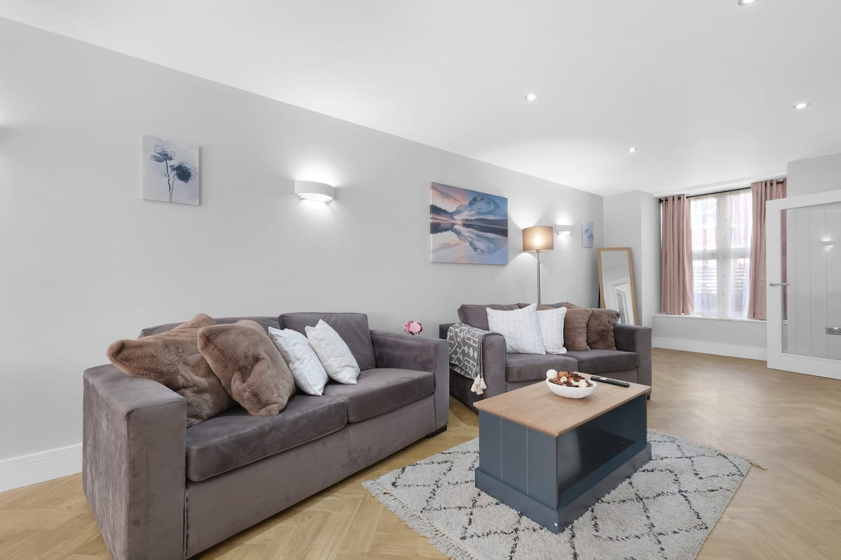 A modern living room with two grey sofas, a coffee table, and artwork on the walls.
