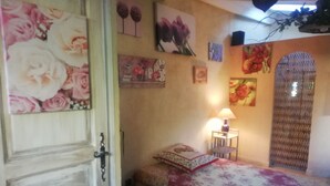 Ein Schlafzimmer mit einem Bett, einem Nachttisch, einer Lampe und Blumenbildern an der Wand.