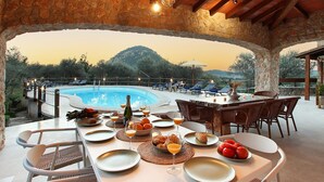 A dining area with a pool view, stone walls, and wooden beams. - Holiday Home "Alordes" with Mountain View, Pool, Garden & Wi-Fi (Illes Balears)