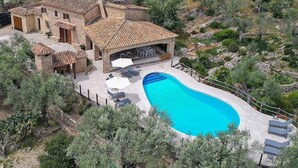 A villa with a swimming pool, outdoor seating, and a stone facade. - Holiday Home "Alordes" with Mountain View, Pool, Garden & Wi-Fi (Illes Balears)