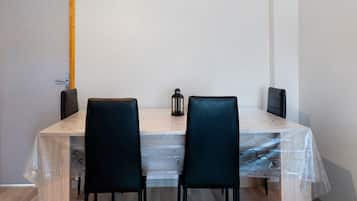 Habitació amb taula de fusta, dues cadires negres, un llum de llanternatge negre i una porta de fusta.