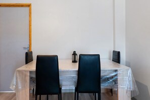 Een kamer met een houten tafel, twee zwarte stoelen, een zwarte lantaarn en een houten deur.