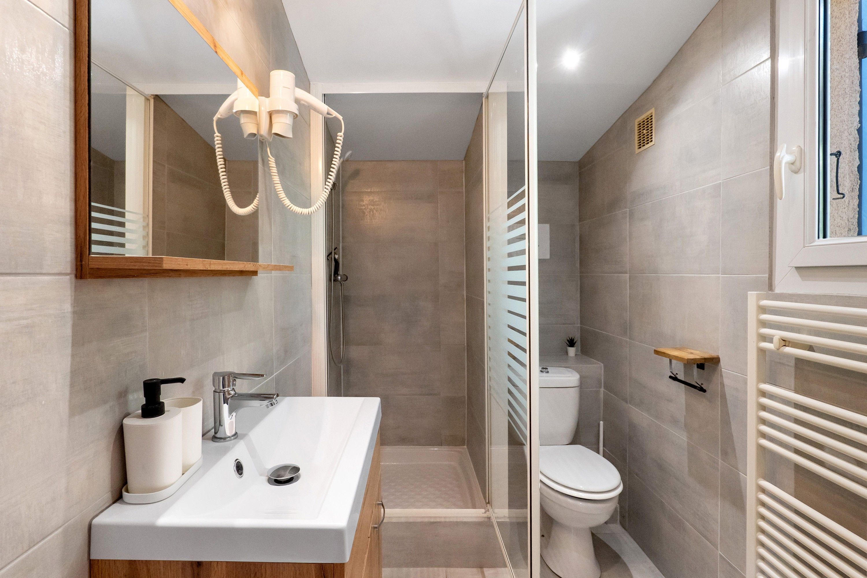Une salle de bain moderne avec une douche à parois de verre, un lavabo blanc avec un miroir et des toilettes.