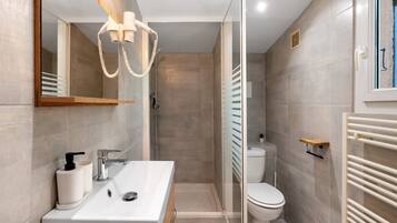 Une salle de bain moderne avec une douche à parois de verre, un lavabo blanc avec un miroir et des toilettes.