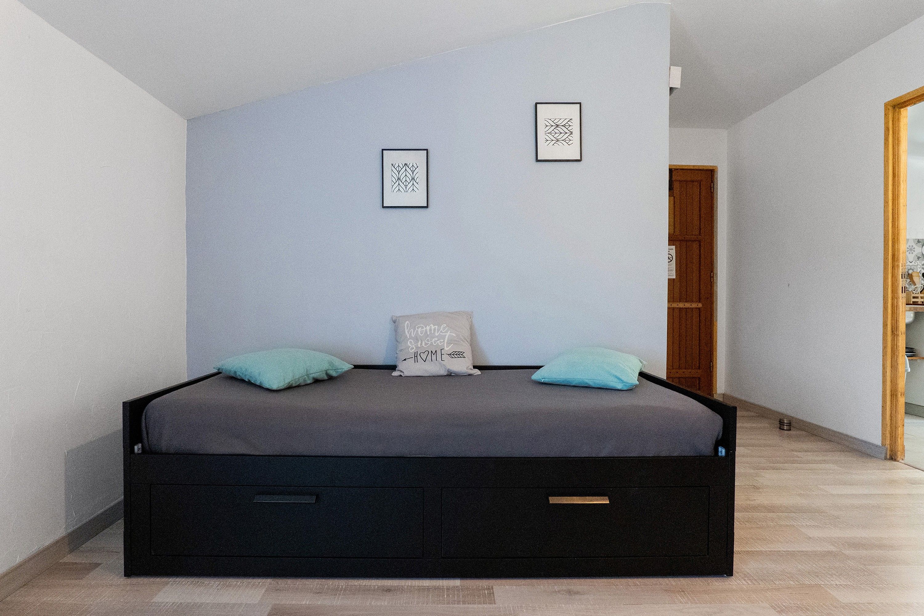 Ein Schlafzimmer mit einem Bett, zwei Kissen, einem Nachttisch und einer Tür.