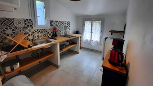 A compact kitchen with a sink, wooden countertop, and a coffee machine.