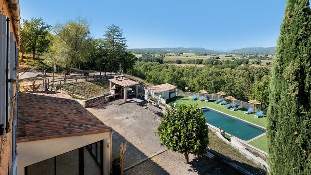 Área de piscina com espreguiçadeiras e vista para o campo.