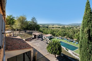 Un espace piscine avec des chaises longues et une vue sur la campagne.