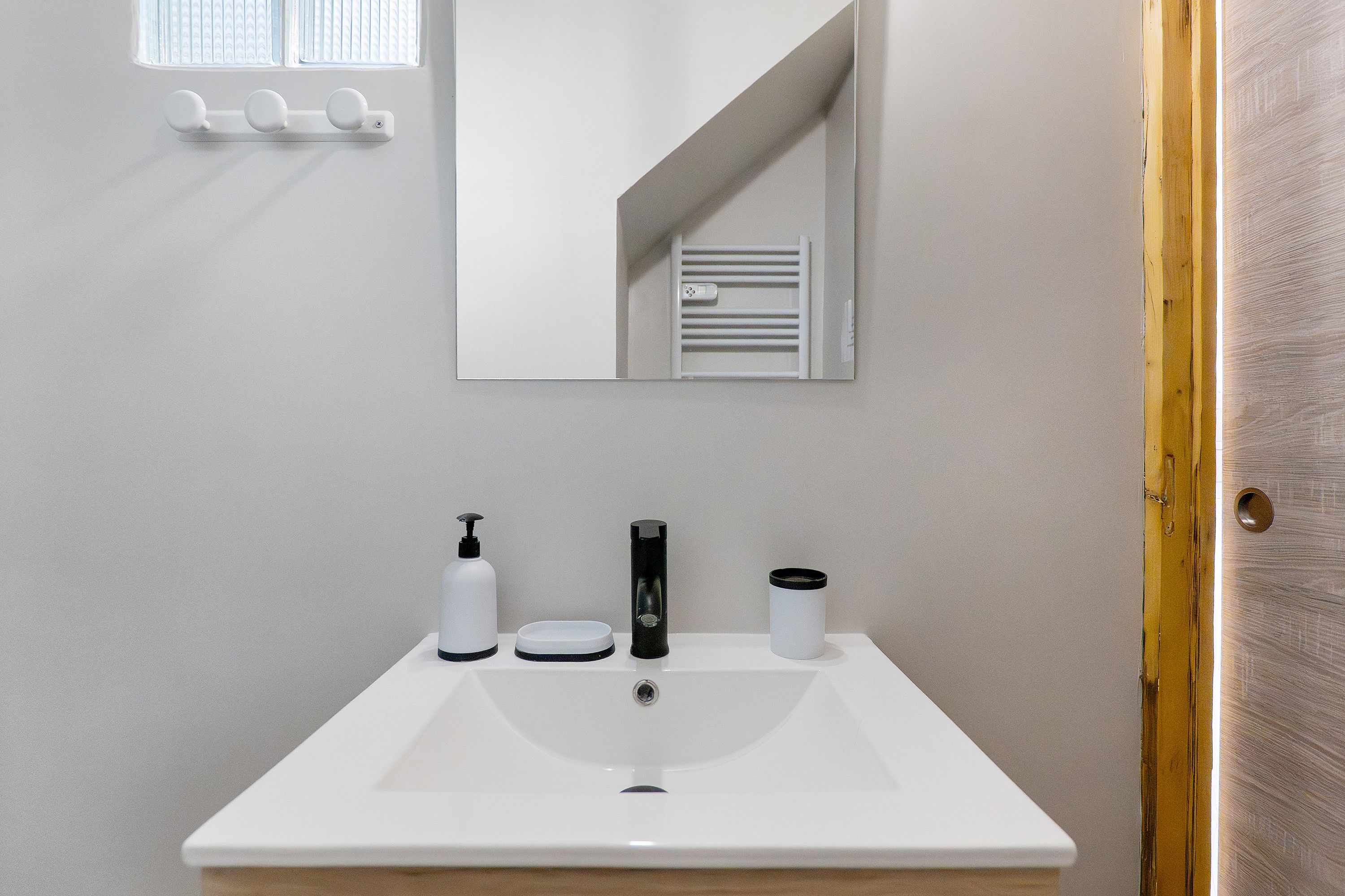 A bathroom with a white sink, a mirror, and a window with blinds.