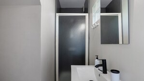 Ein Badezimmer mit einem weißen Waschbecken, einem schwarzen Wasserhahn und einem Spiegel darüber.