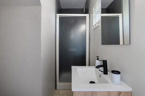 Ein Badezimmer mit einem weißen Waschbecken, einem schwarzen Wasserhahn und einem Spiegel darüber.