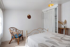 Ein Schlafzimmer mit Bett, Stuhl, Nachttisch, Kleiderschrank und einer Pendelleuchte.