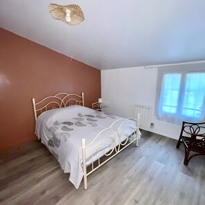 Una camera da letto con un letto, un termosifone, una finestra e una sedia.