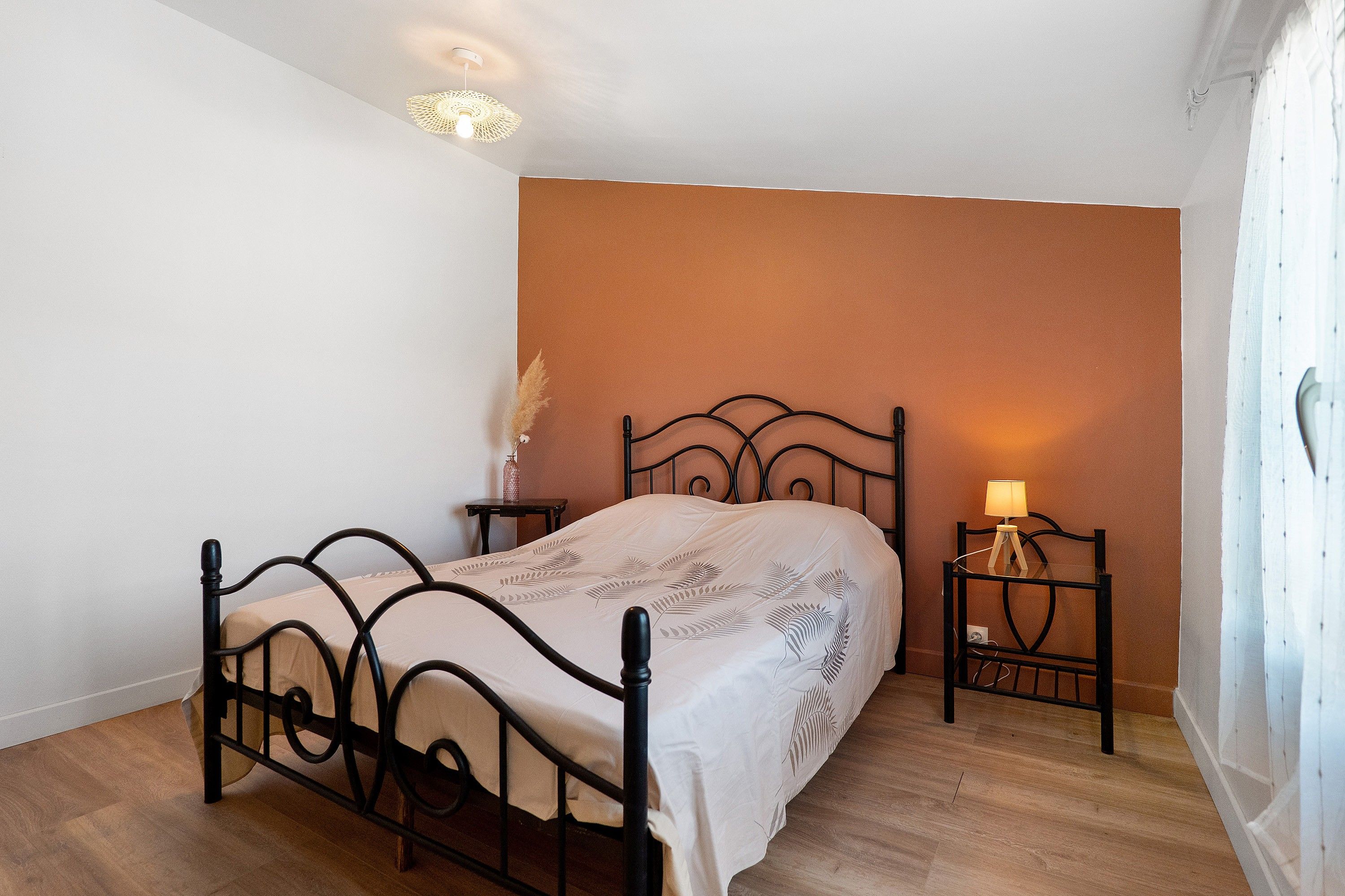 A bedroom with a bed, bedside tables, a lamp, and a wall-mounted light fixture.