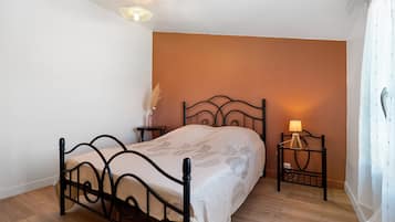 A bedroom with a bed, bedside tables, a lamp, and a wall-mounted light fixture.