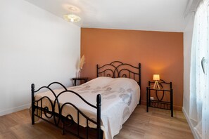 A bedroom with a bed, bedside tables, a lamp, and a wall-mounted light fixture.