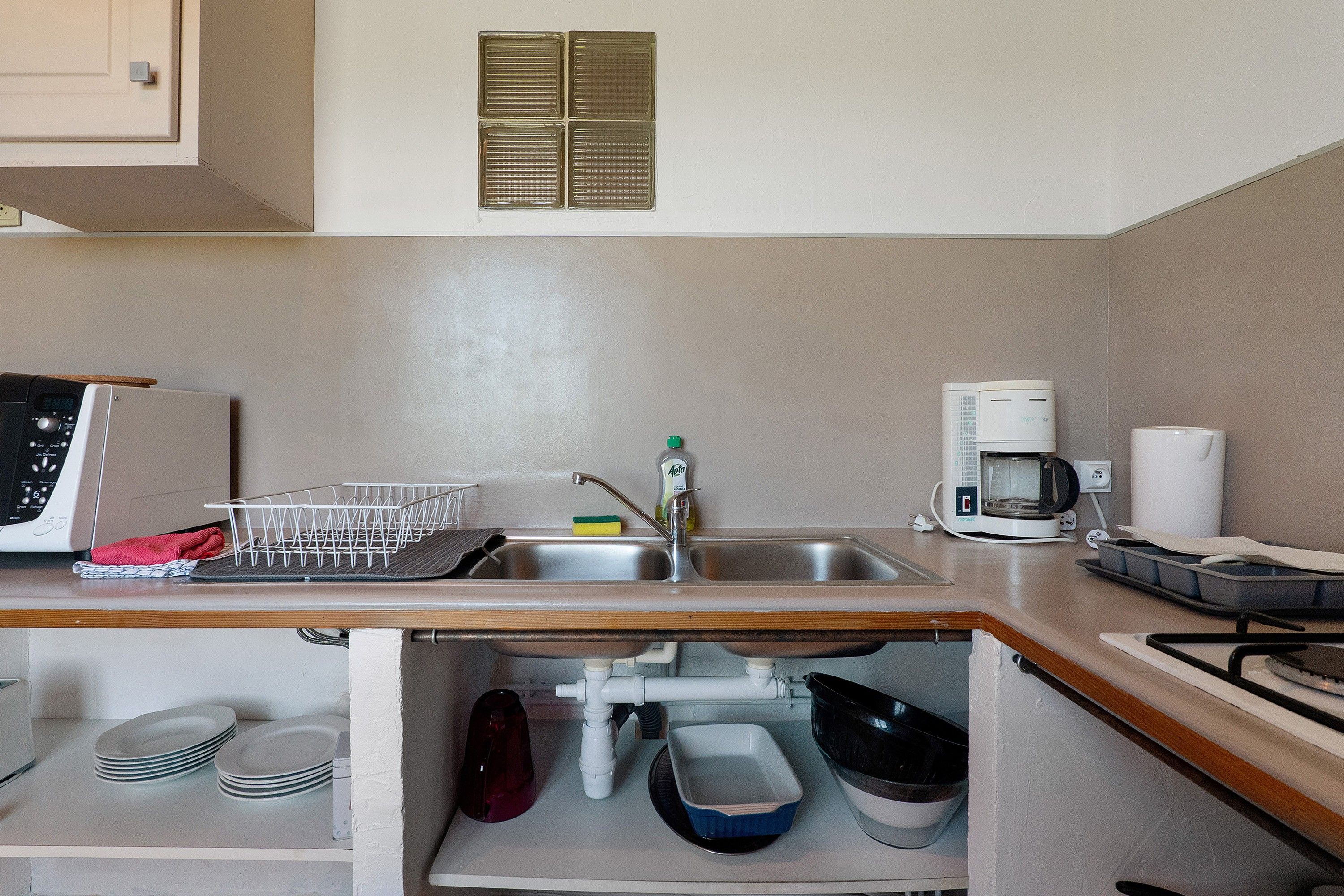 A compact kitchen with a built-in dishwasher, a coffee maker, and a sink.