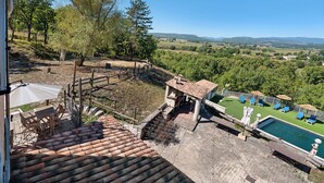 Eine Dachterrasse mit Schwimmbad, Sitzgelegenheiten im Freien und Blick auf die Landschaft.