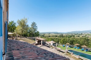Une terrasse avec vue sur une piscine et un paysage de campagne.