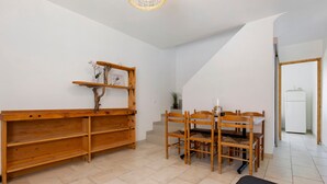 Une pièce avec un banc en bois, une table à manger avec des chaises, et un réfrigérateur blanc à l’arrière-plan.