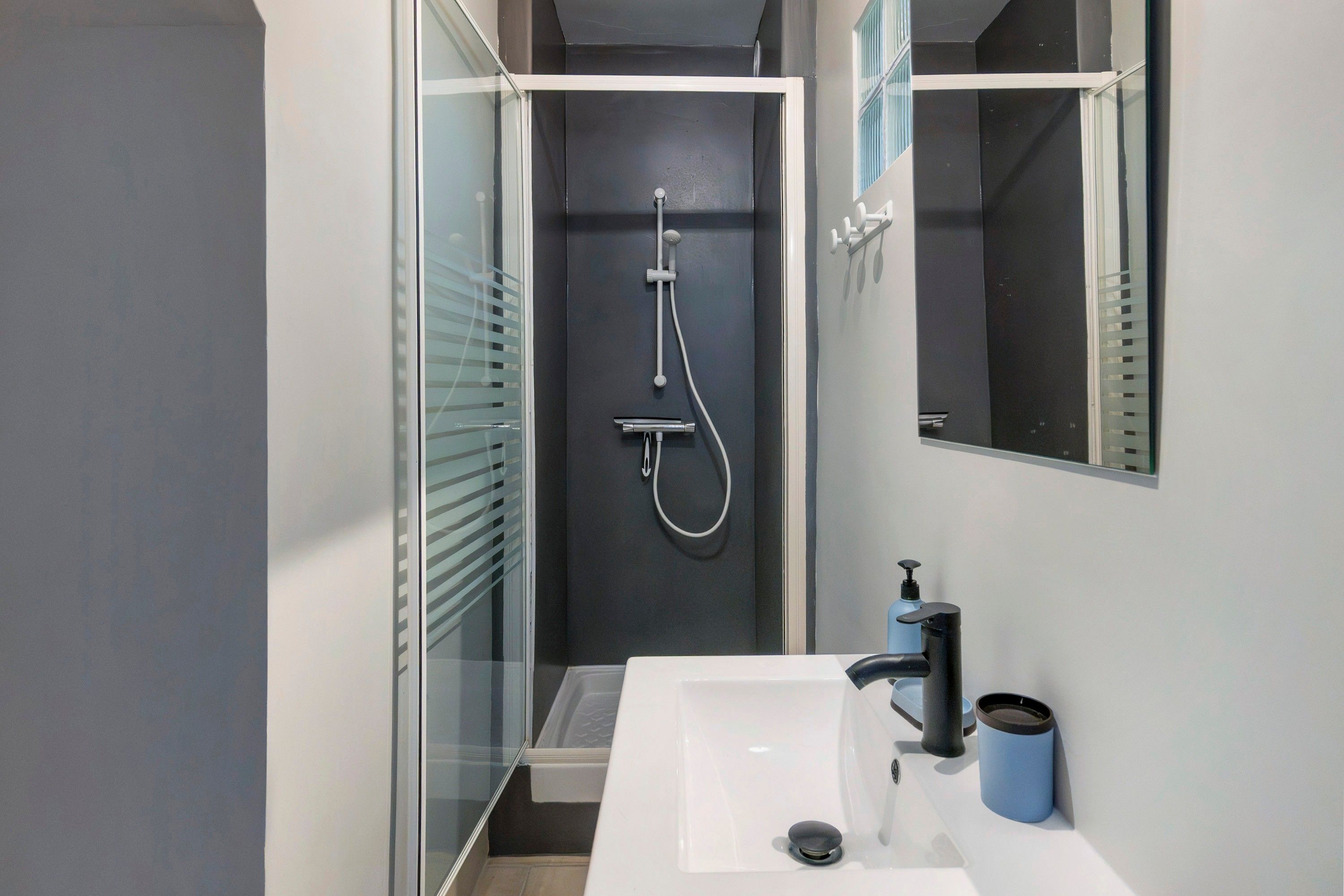 Un baño moderno con cabina de ducha de vidrio, lavabo blanco y espejo.