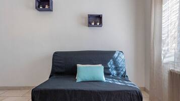 Een kamer met een bed, twee wandplanken en een raam.