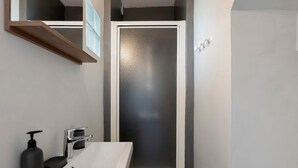 Une salle de bain avec un lavabo blanc, un distributeur de savon noir et un miroir au-dessus.