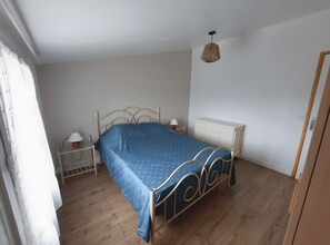 Et soveværelse med seng, natborde, kommode og en hængende lampe.