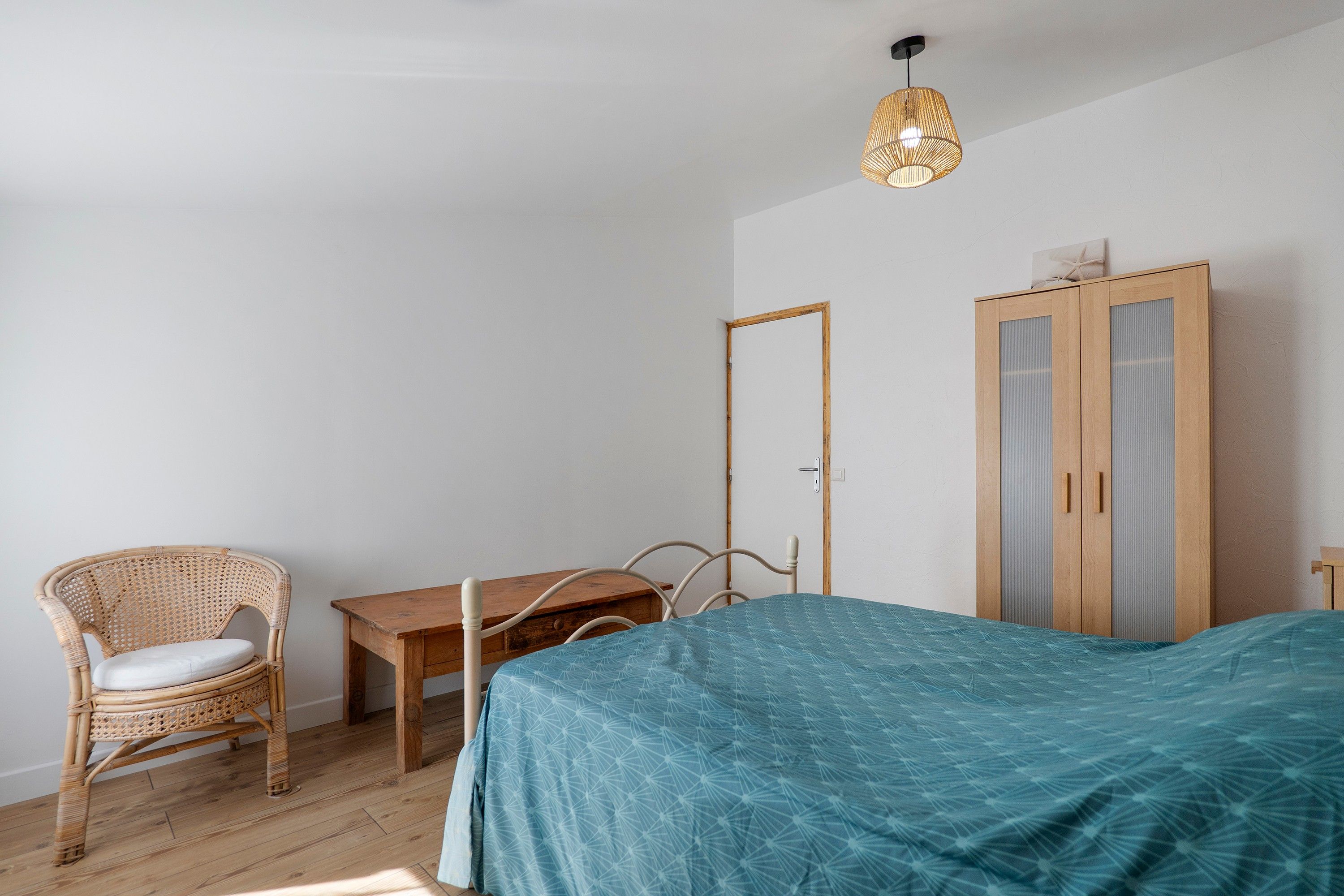 Ein Schlafzimmer mit einem Bett, einem Sessel, einem kleinen Tisch und einem Kleiderschrank.