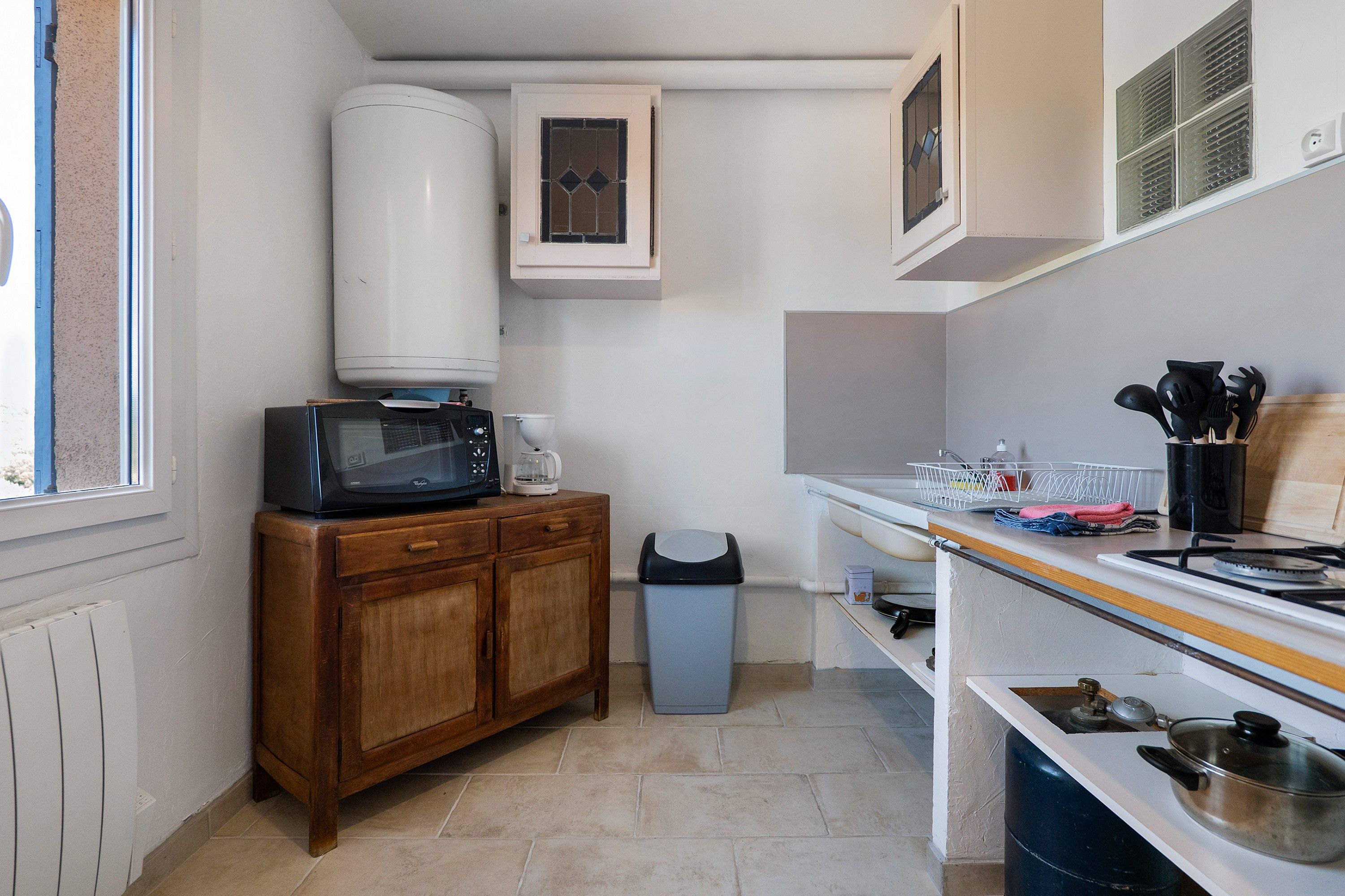 Una cocina compacta con microondas, cafetera y estufa a gas.