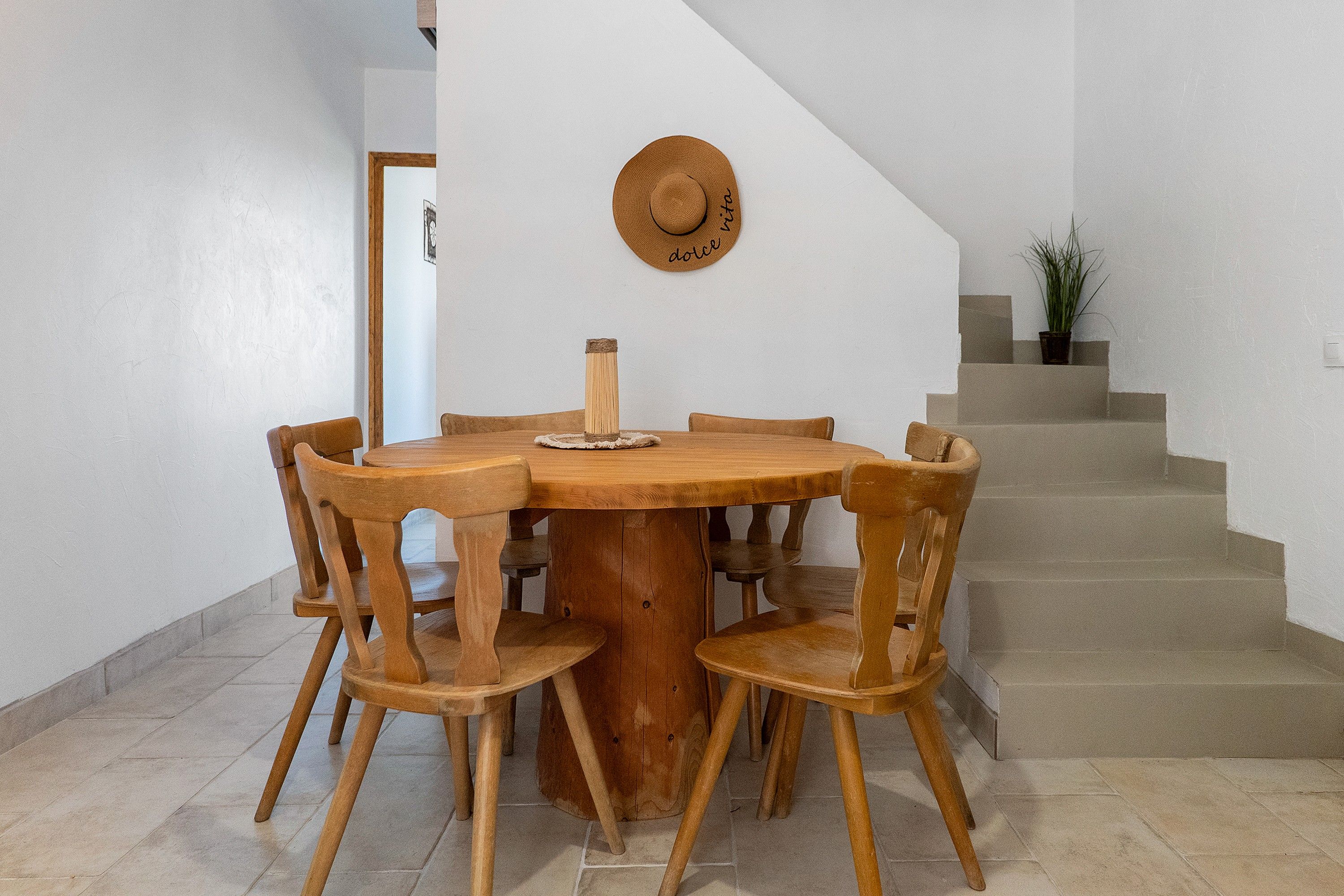 Ein Holztisch mit sechs Stühlen, ein runder Holz-Tischläufer und eine Holzwanddekoration mit Text.